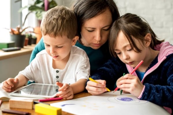 Madre ayudando a sus hijos a hacer sus deberes escolares