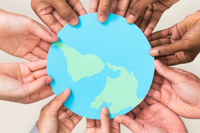 Personas sosteniendo un planeta tierra de papel simbolizando la responsabilidad social empresarial
